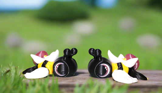 Three cartoon bee figurines on a white surface with a light background