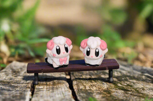 Two small pink and white character figurines on a light gray background